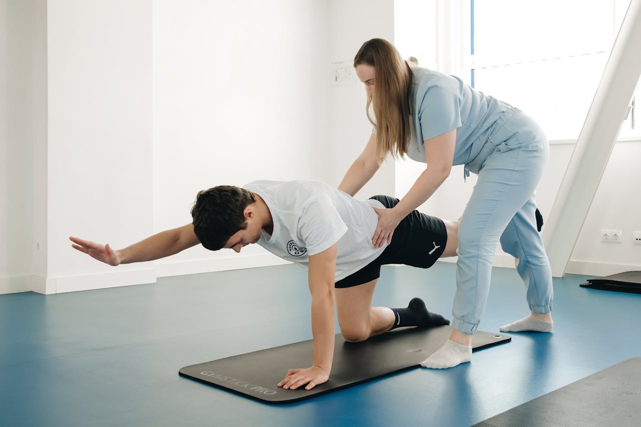 A physiotherapist guides a patient's exercise on a mat in a Vilnius gym.
